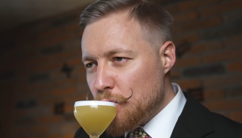 Bartender drinks clarified milk punch from a glass