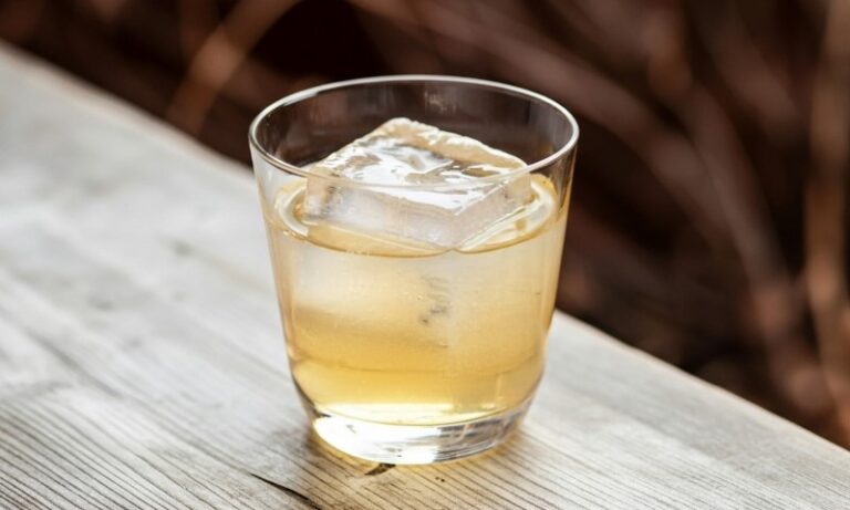 A glass of clarified milk punch on a wooden table